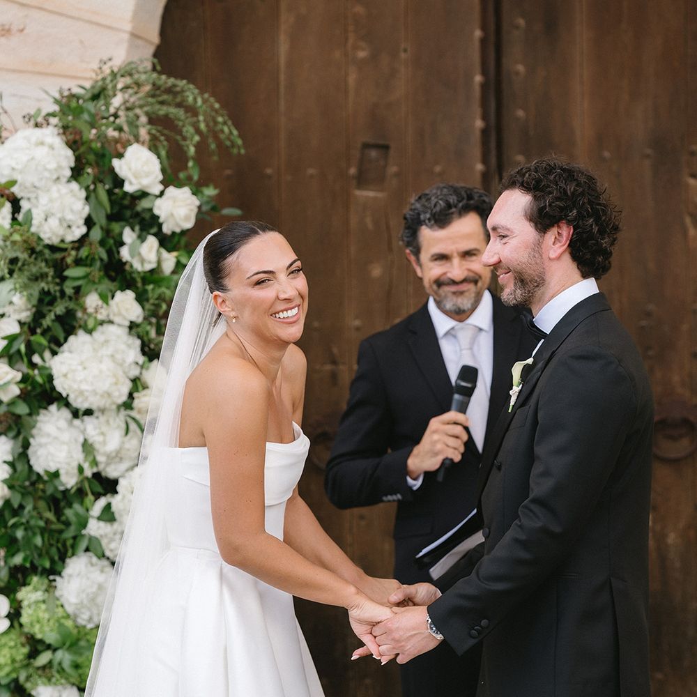 bride-smiles-for-wedding-ceremony-holding-hands-with-groom