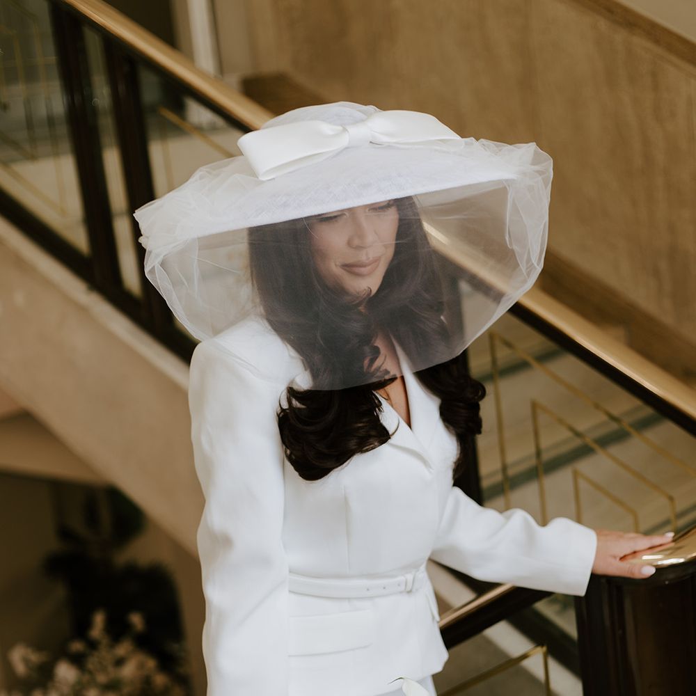 bride-wearing-wide-brimmed-hat-with-bow-and-veil-for-ceremony