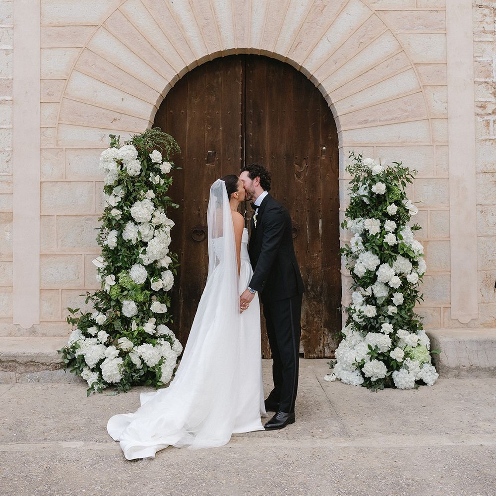 couple-have-first-kiss-with-white-flower-column-altar-decor