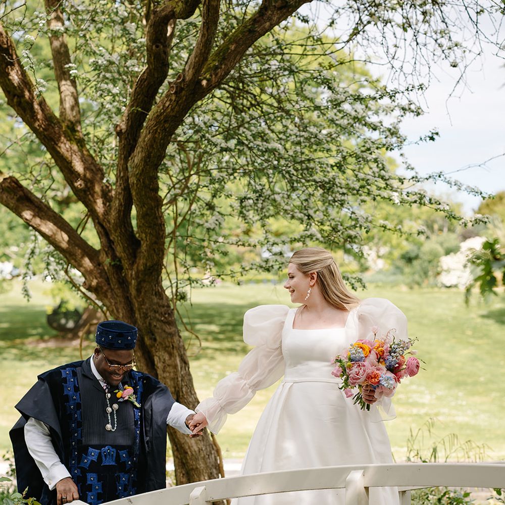 groom-in-agbada-with-bride-in-puff-sleeve-wedding-dress-walking-across-bridge