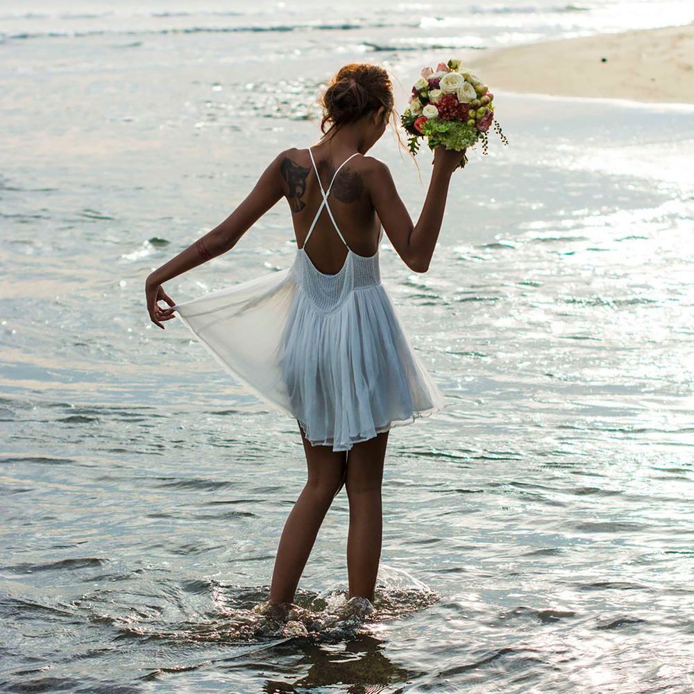 Destination wedding shoot with bride wearing a short white dress in the sea