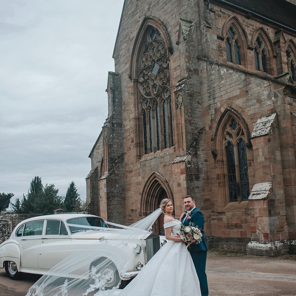 bride-with-floral-embroidered-wedding-veil-with-groom-outside-church