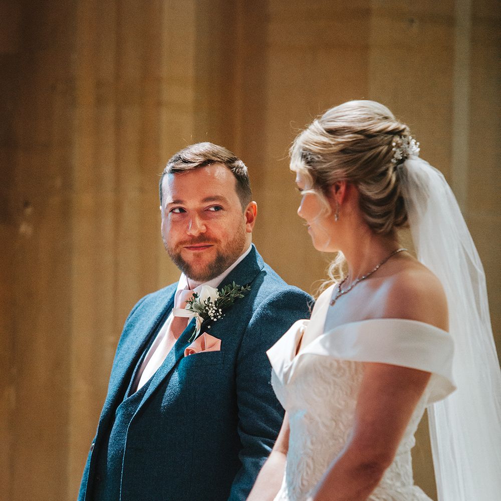 groom-in-blue-wedding-suit-looks-up-at-bride