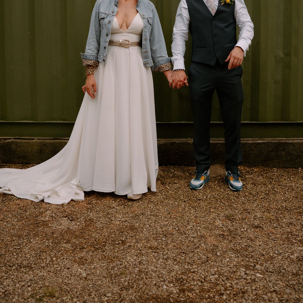 bride-in-boho-wedding-dress-and-denim-jacket-holding-hands-with-groom