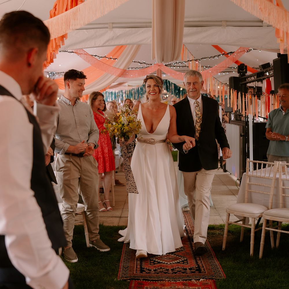 father-of-the-bride-walks-bride-down-the-aisle-with-peach-orange-streamer-decor