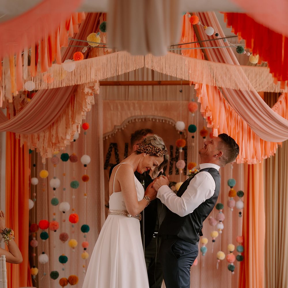 peach-orange-altar-decor-as-bride-and-groom-laugh-during-wedding-ceremony