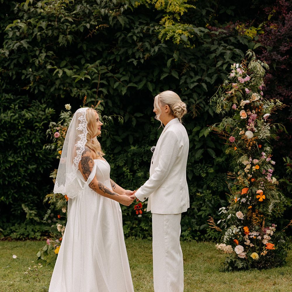 brides-hold-hands-for-their-outdoor-wedding-ceremony-on-rug