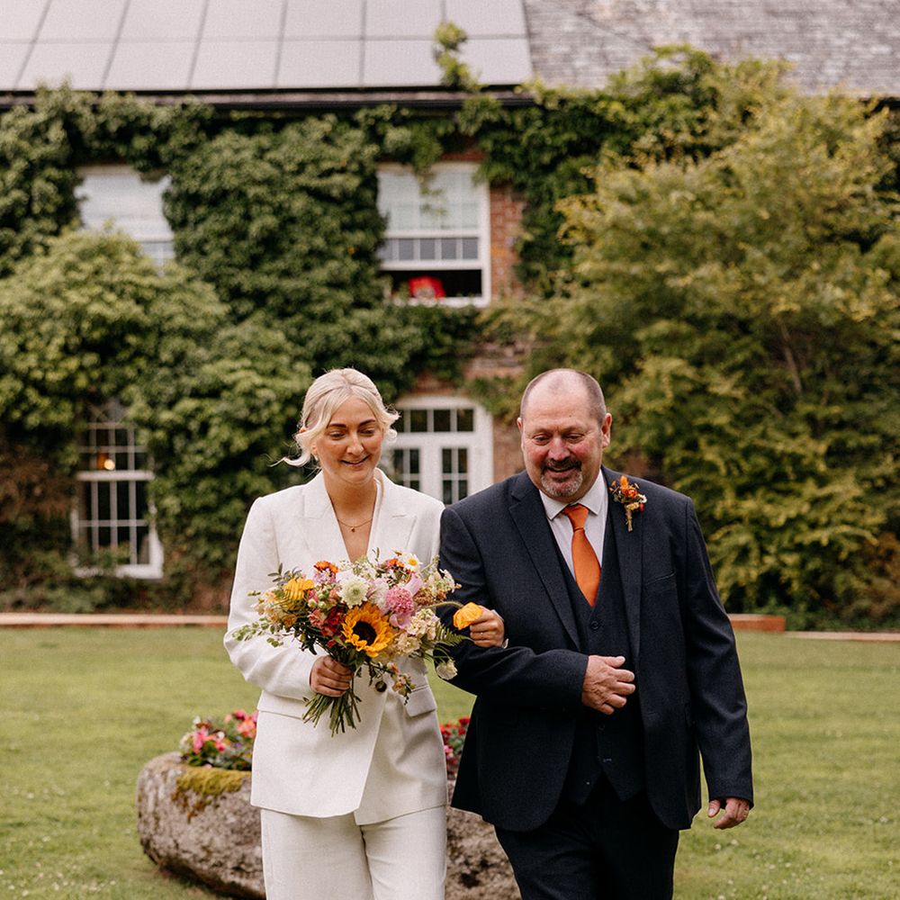 father-of-the-bride-walks-bride-in-white-bridal-suit-down-the-aisle