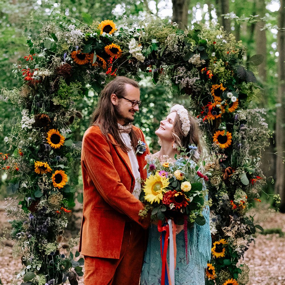 sunflower-wedding-arch-with-groom-in-orange-suit-and-bride-in-blue-dress