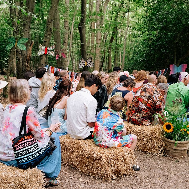 wedding-guests-seated-on-hay-bales-for-woodland-wedding