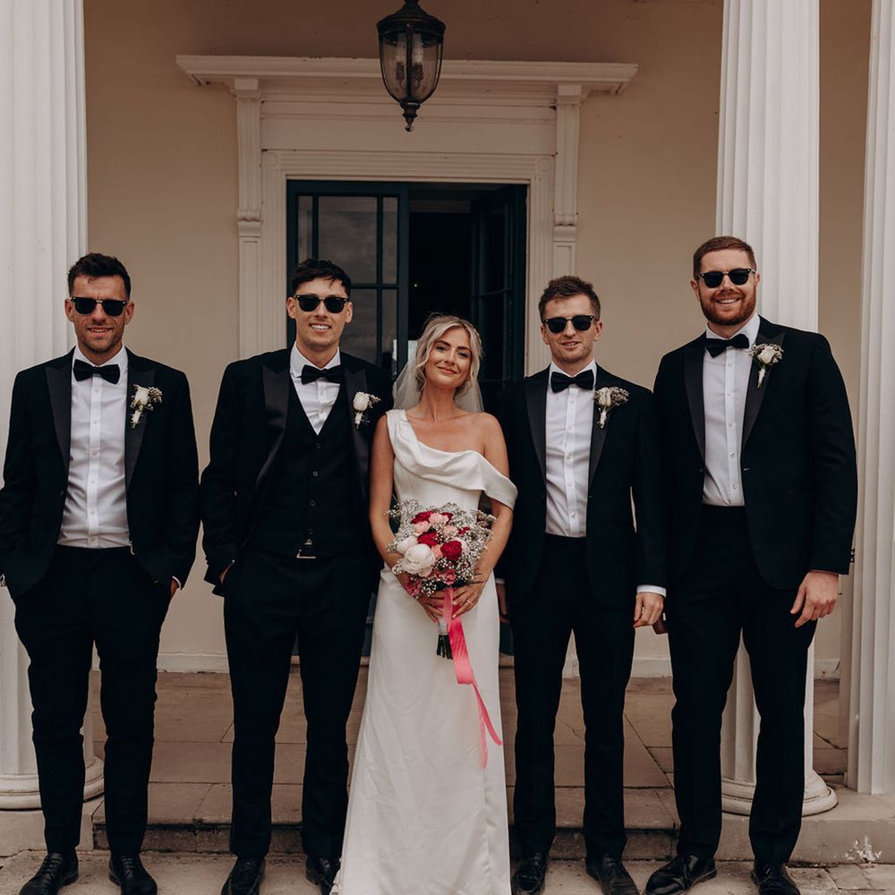 groomsmen-in-black-tuxedos-with-bride