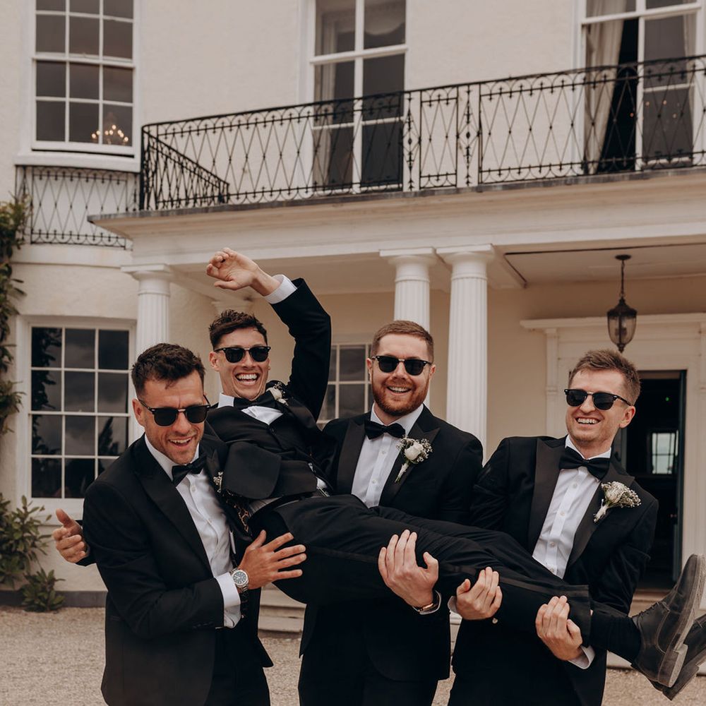 groomsmen-lifts-groom-in-the-air-black-tuxedo
