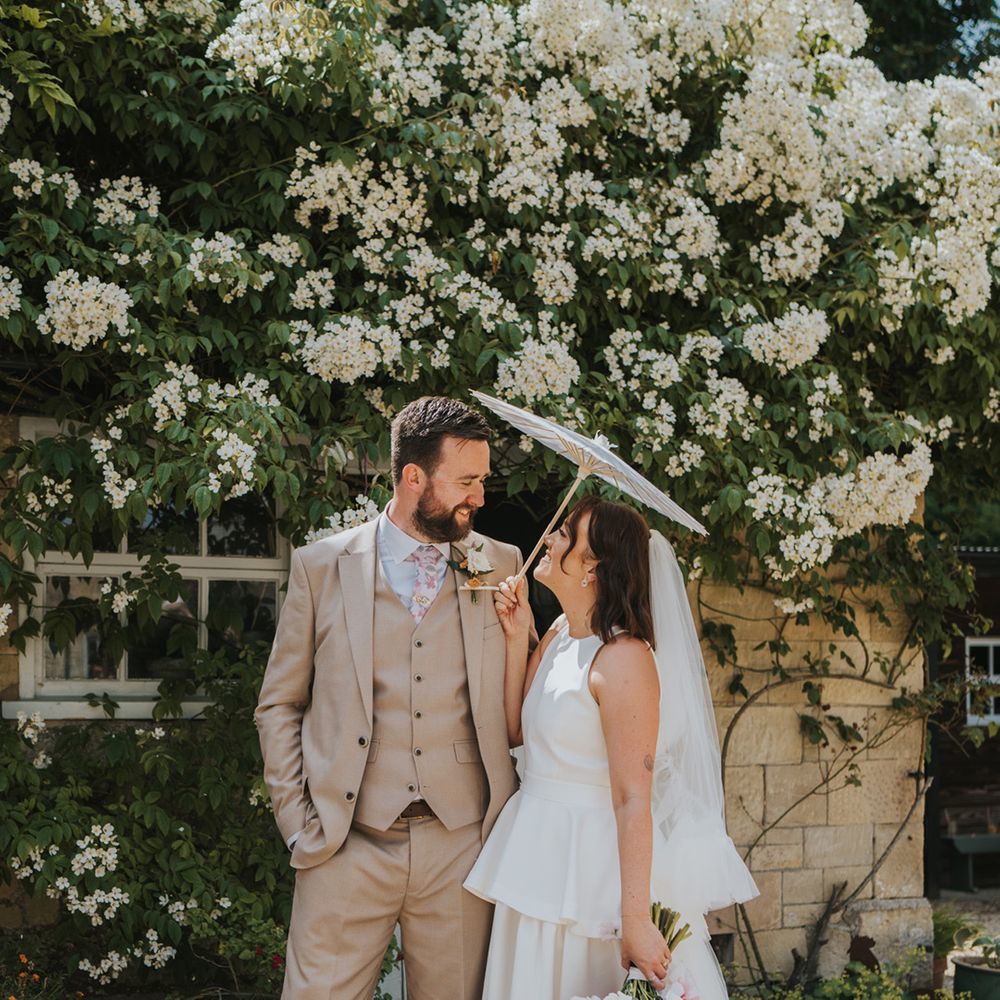 bride-in-peplum-wedding-dress-with-groom-in-beige-suit-with-umbrella
