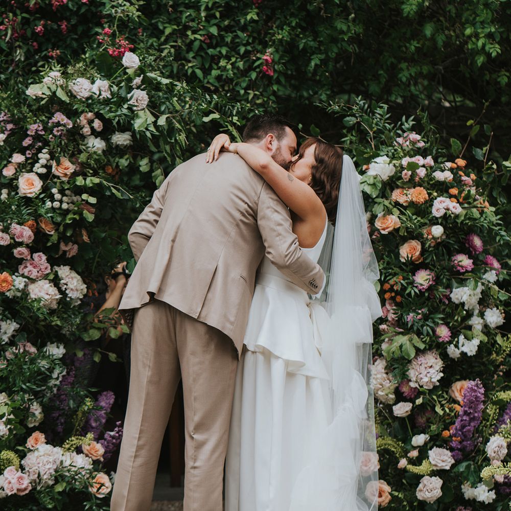 first-kiss-for-couple-in-front-of-wedding-flower-columns