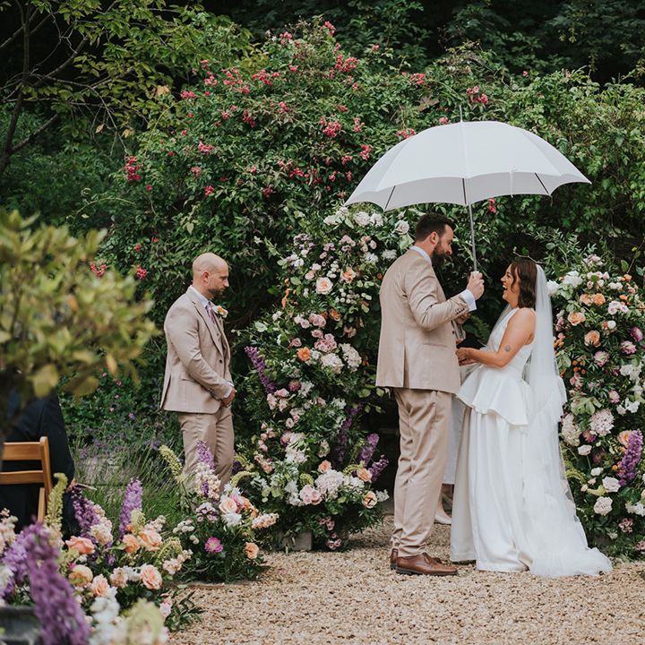 groom-holds-umbrella-for-outdoor-wedding-ceremony-rainy-weather