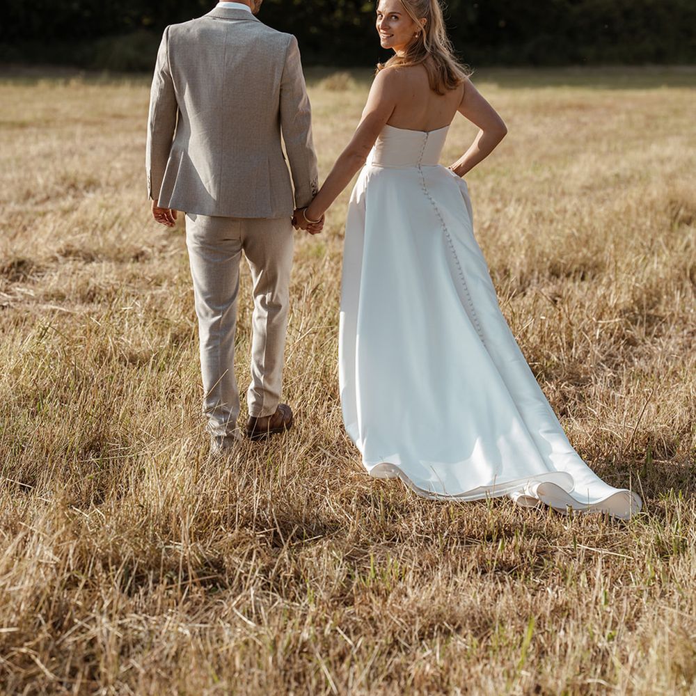 groom-in-beige-wedding-suit-walking-with-bride-in-strapless-wedding-dress