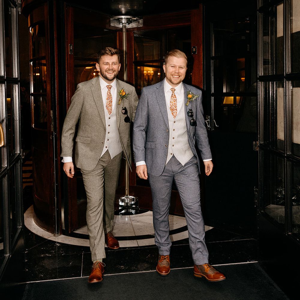 Two grooms in complementary green and blue suits 