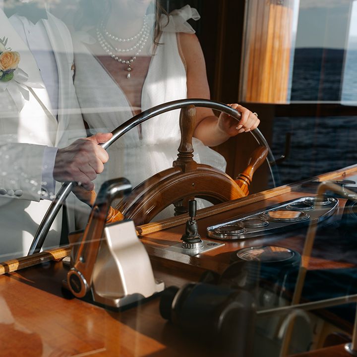 Bride and groom steer the boat at wedding 