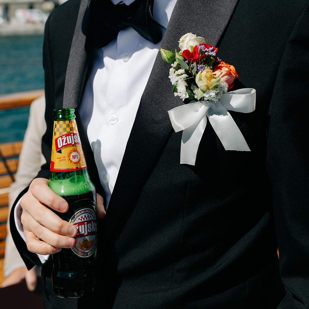 Groomsman in black tuxedo with colourful bouquet with white ribbon