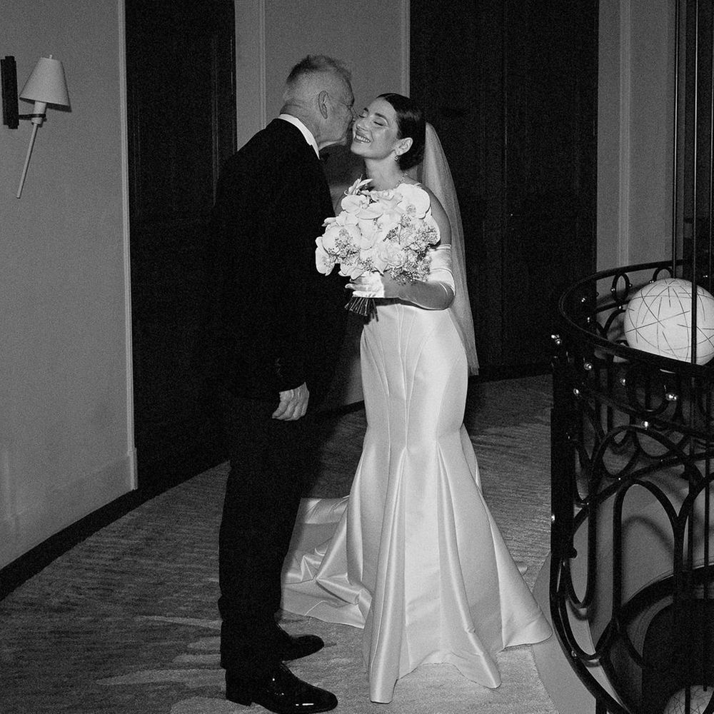 Father of the bride kisses bride on the cheek 