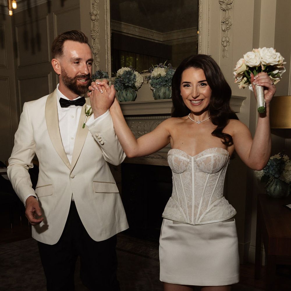 groom-in-white-tuxedo-walking-with-bride-in-corset-and-satin-skirt