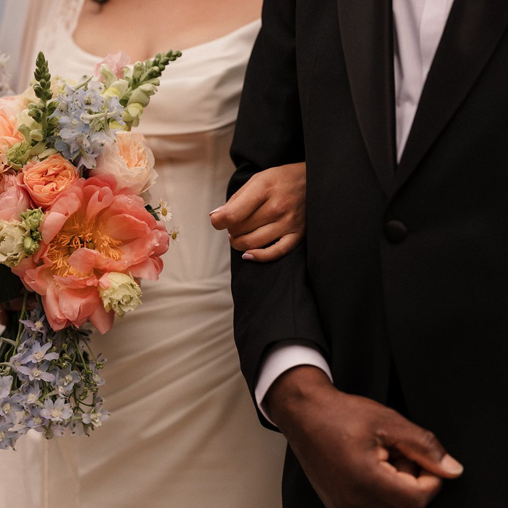 bride-in-corset-style-wedding-dress-and-pastel-bouquet-linking-arms-with-father-of-the-bride