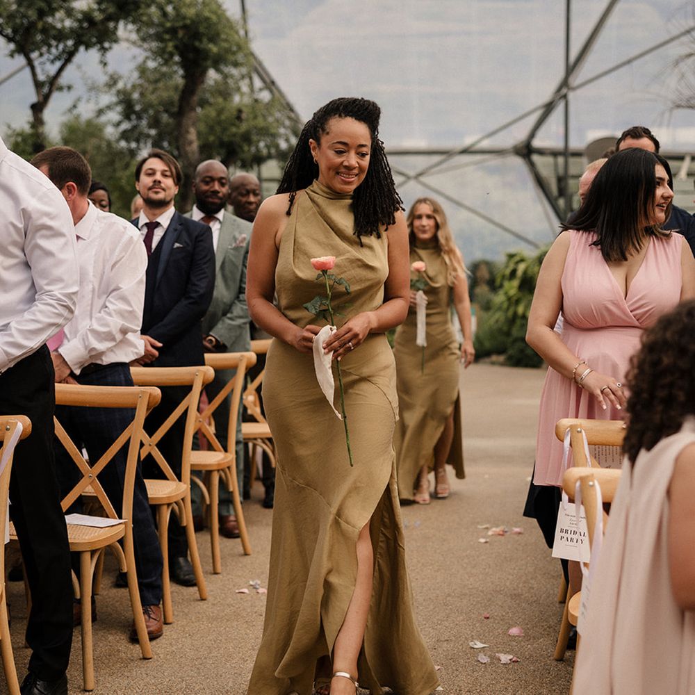 bridesmaids-in-olive-green-dresses-walking-down-the-aisle-with-single-stem-flowers