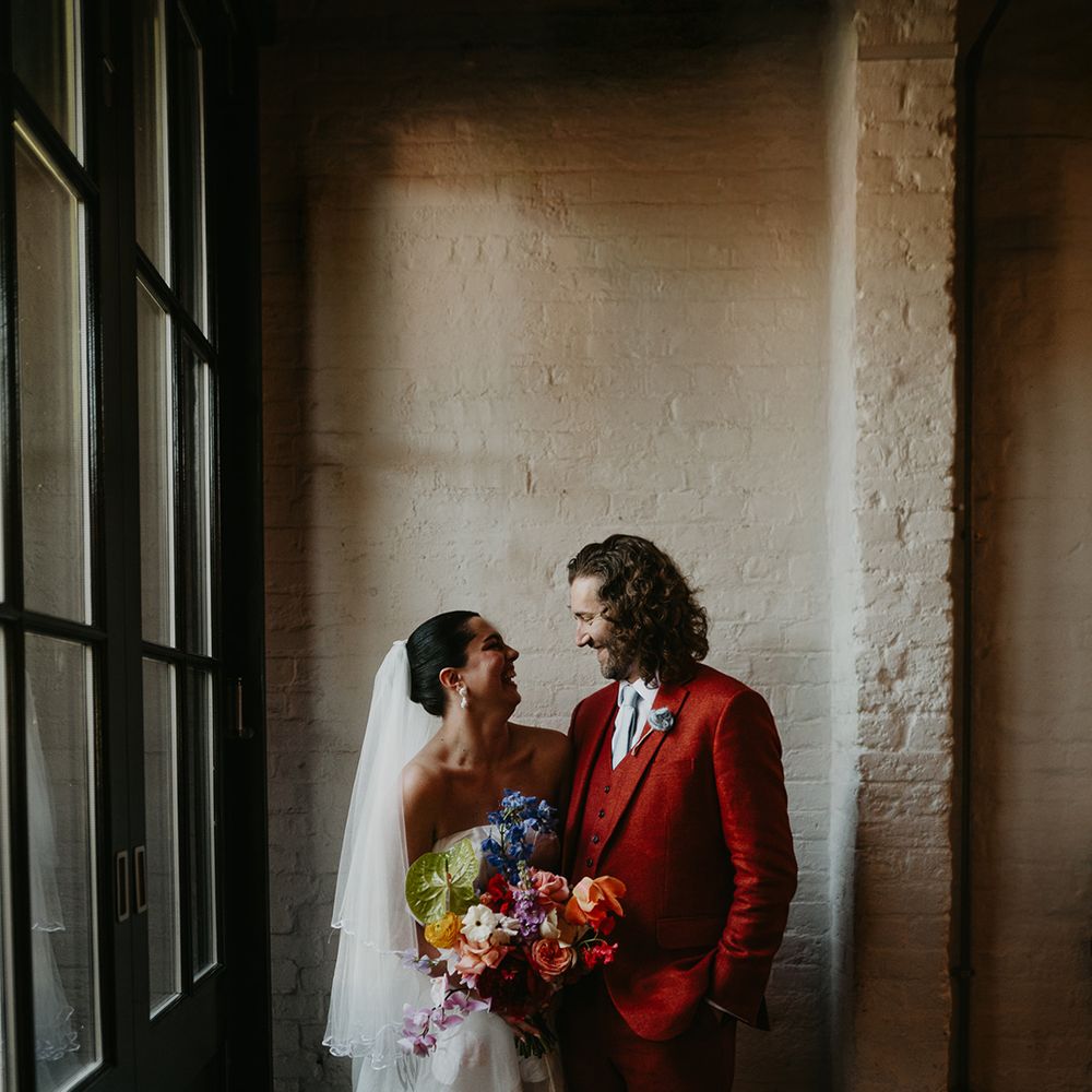 bride-in-floral-wedding-dress-and-groom-in-red-suit-at-modern-city-wedding