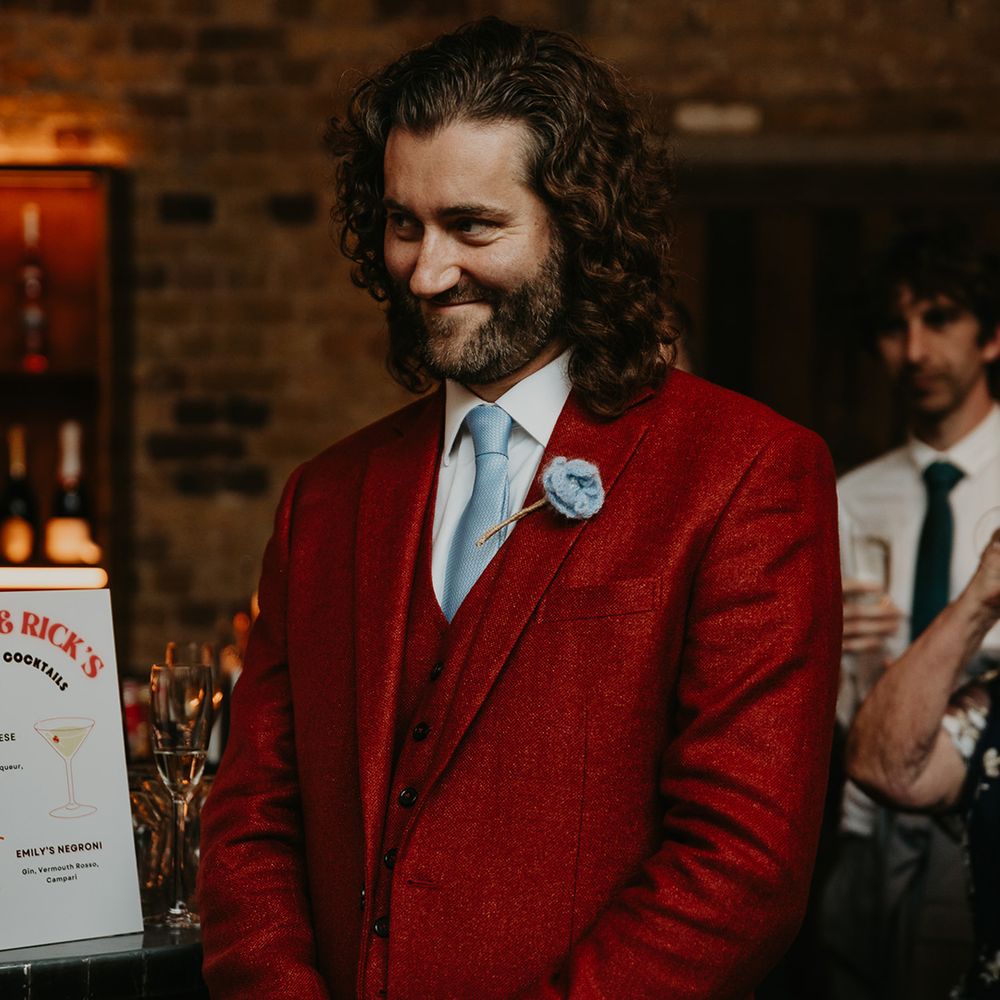 groom-wears-three-piece-dark-red-wedding-suit-and-light-blue-tie-and-floral-buttonhole