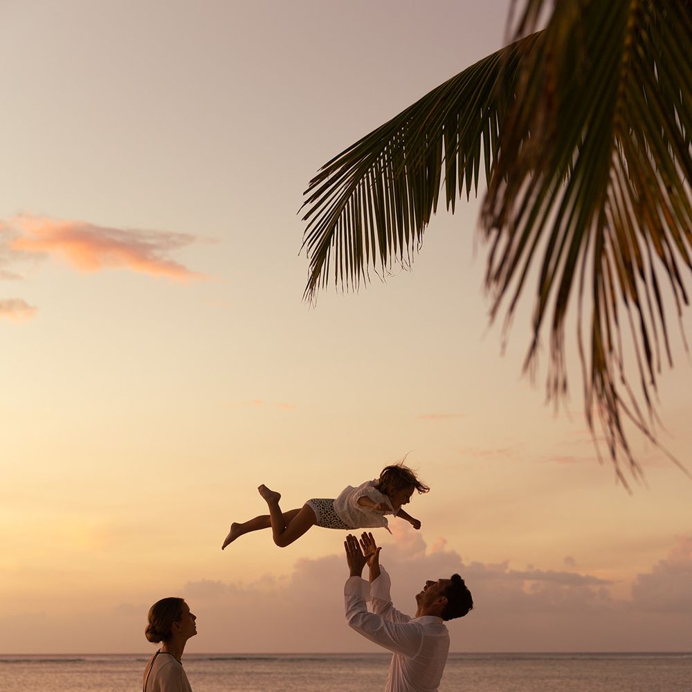 couple-lifts-child-in-the-air-on-beach
