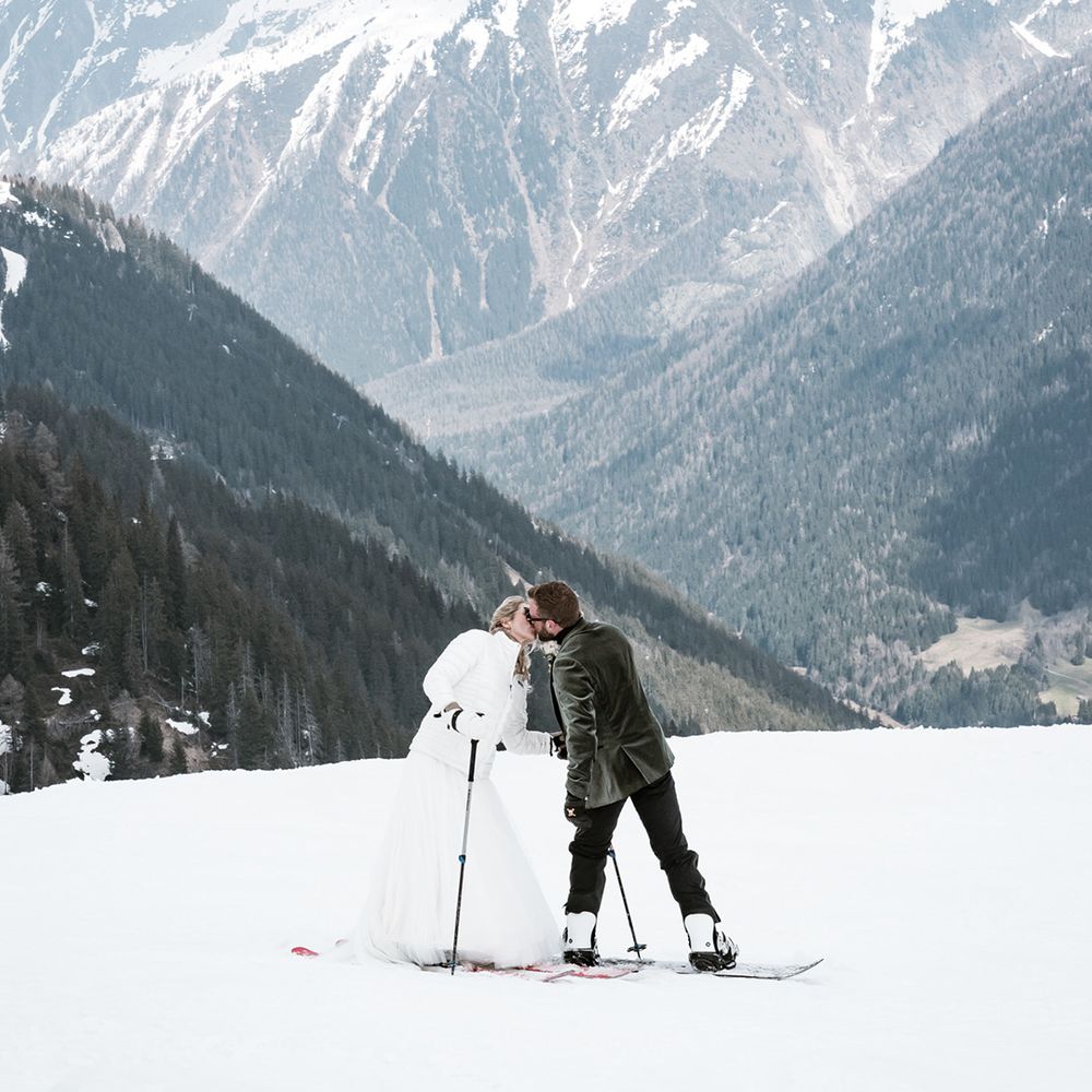 couple-kisses-on-snowy-summit-with-french-alps-backdrop