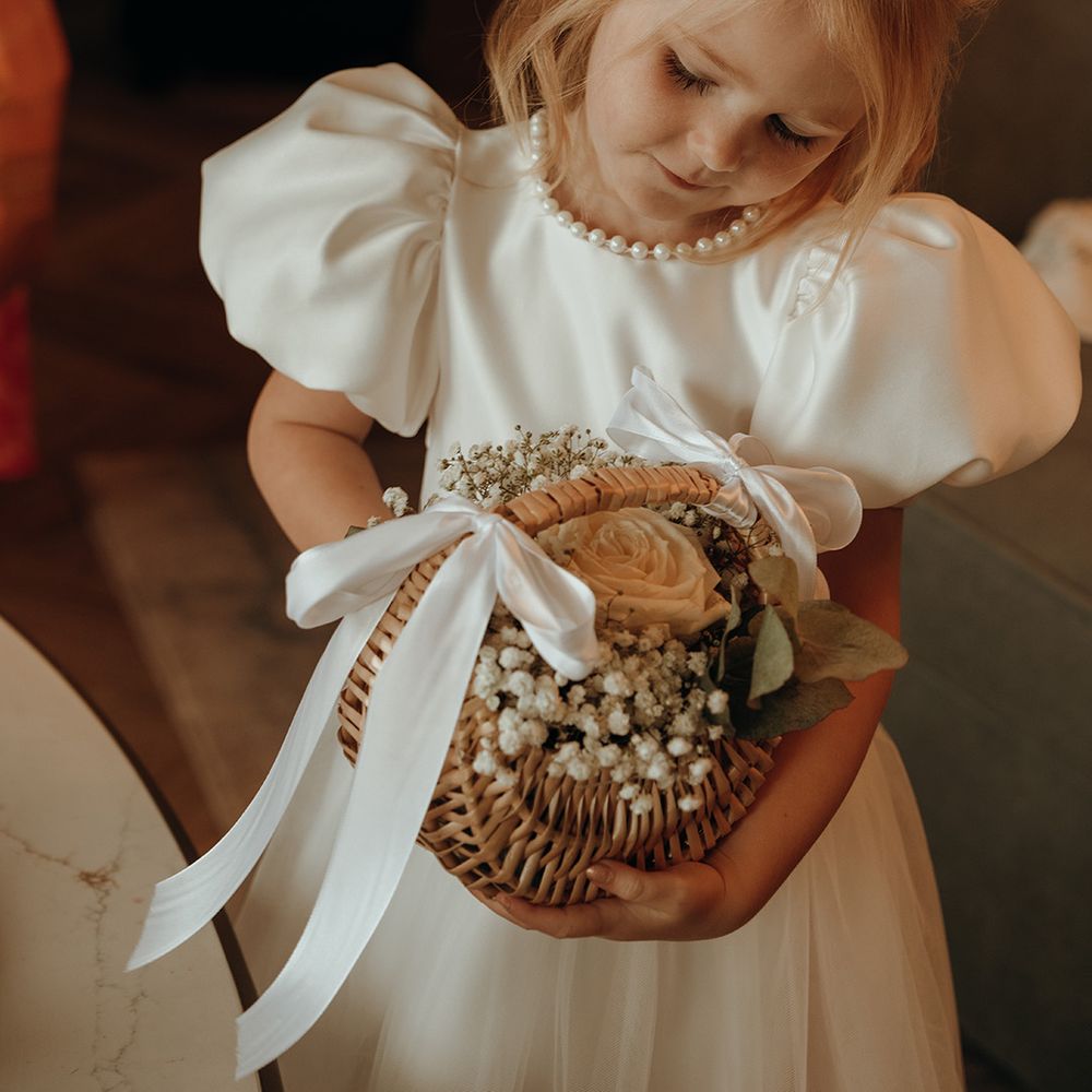 flower-girl-in-puff-sleeve-dress-with-wicker-basket-with-flowers