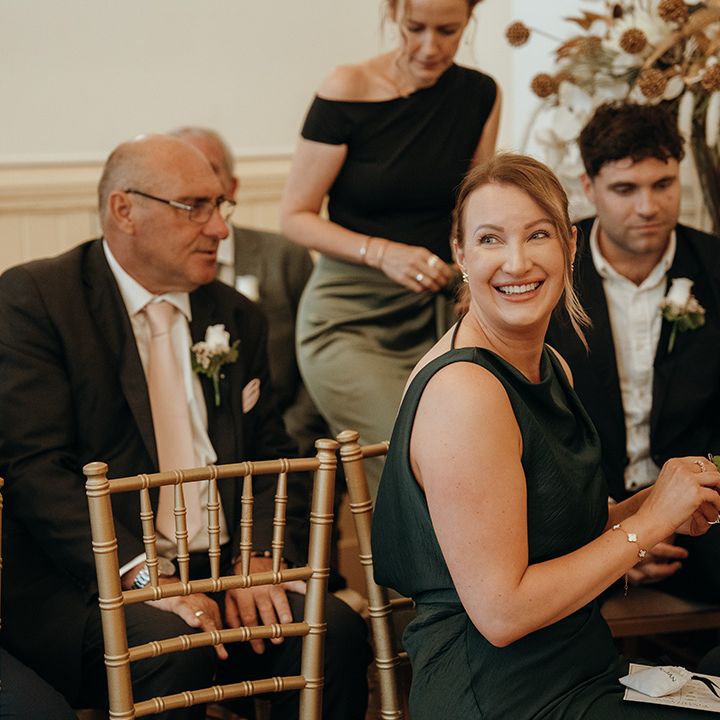 wedding-guests-on-wooden-ceremony-chairs-in-green-outfits