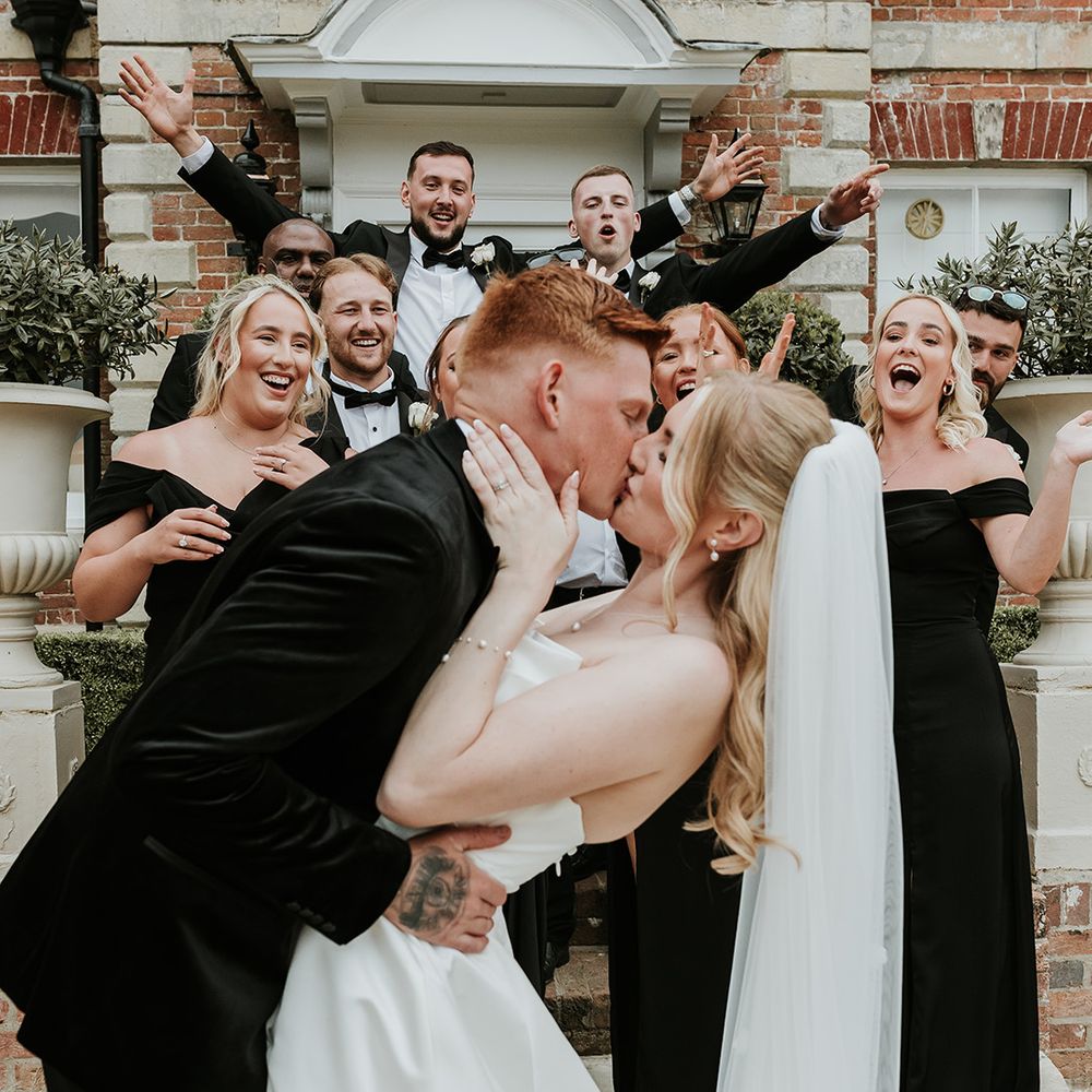 wedding-party-celebrates-as-bride-and-groom-kiss