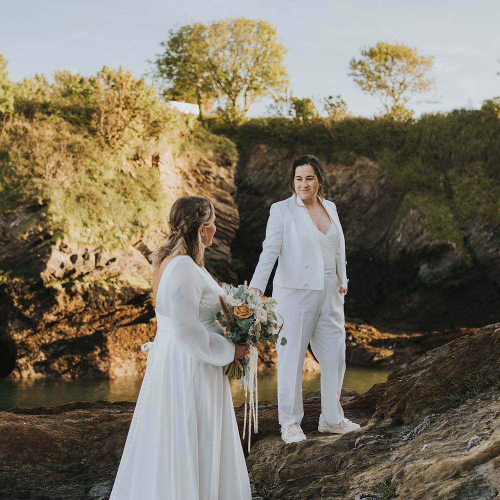 bride-in-tailored-white-wedding-suit-holding-hands-with-bride-in-wedding-dress