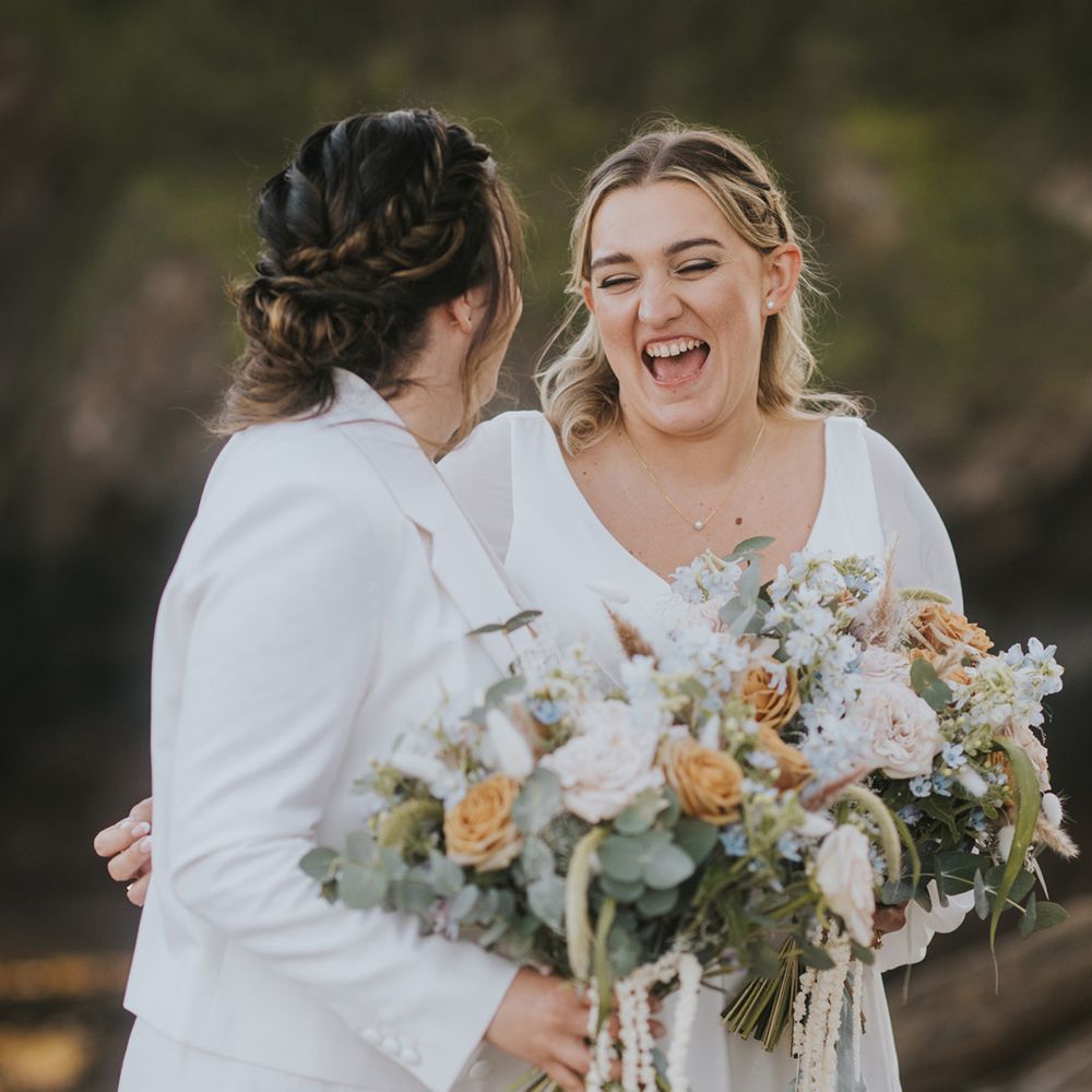 brides-laughing-together-with-orange-white-wedding-bouquets