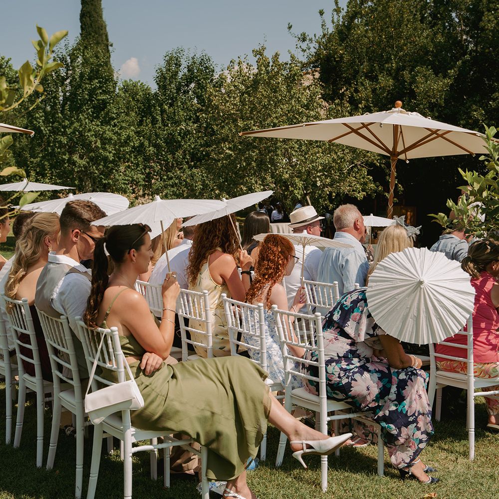 wedding-guesst-with-umbrellas-seated-for-wedding-ceremony