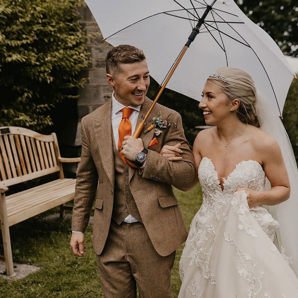 Couple under large white golf umbrella on wedding day