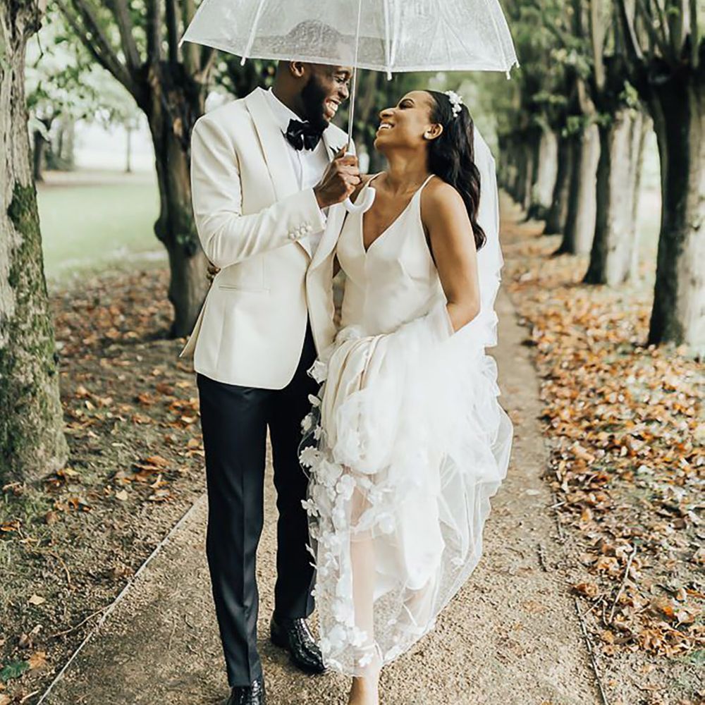 Bride and groom smiling at each other under clear umbrella