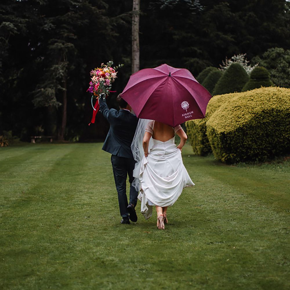 Couple walks around their venue under colourful purple umbrella