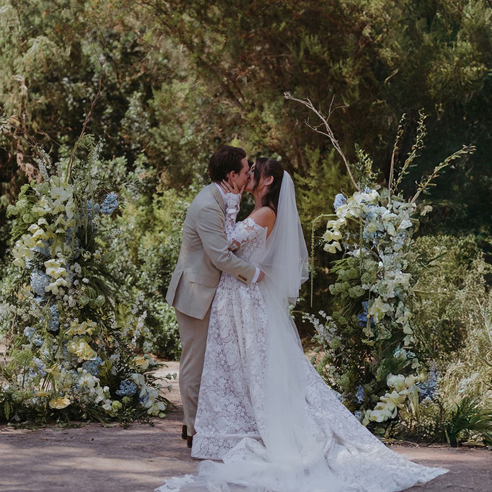 first-kiss-for-bride-and-groom-in-front-of-floral-arrangements-at-ibiza-wedding