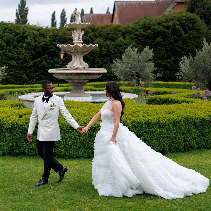 couple-walks-around-gardens-of-country-house-wedding