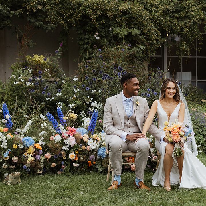 bride-and-groom-seated-for-outdoor-wedding-with-colourful-flowers