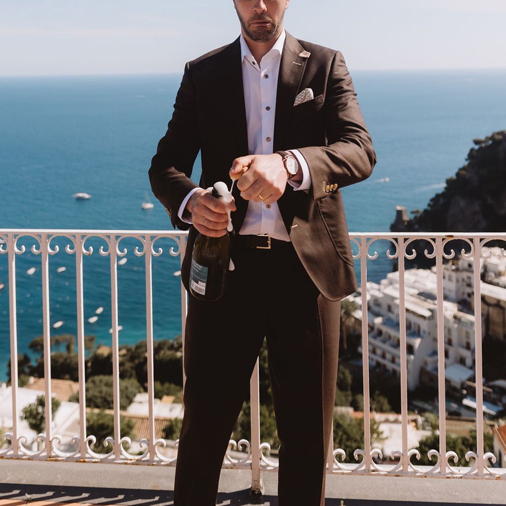 groom-pulls-funny-face-as-he-pops-bottle-of-champagne