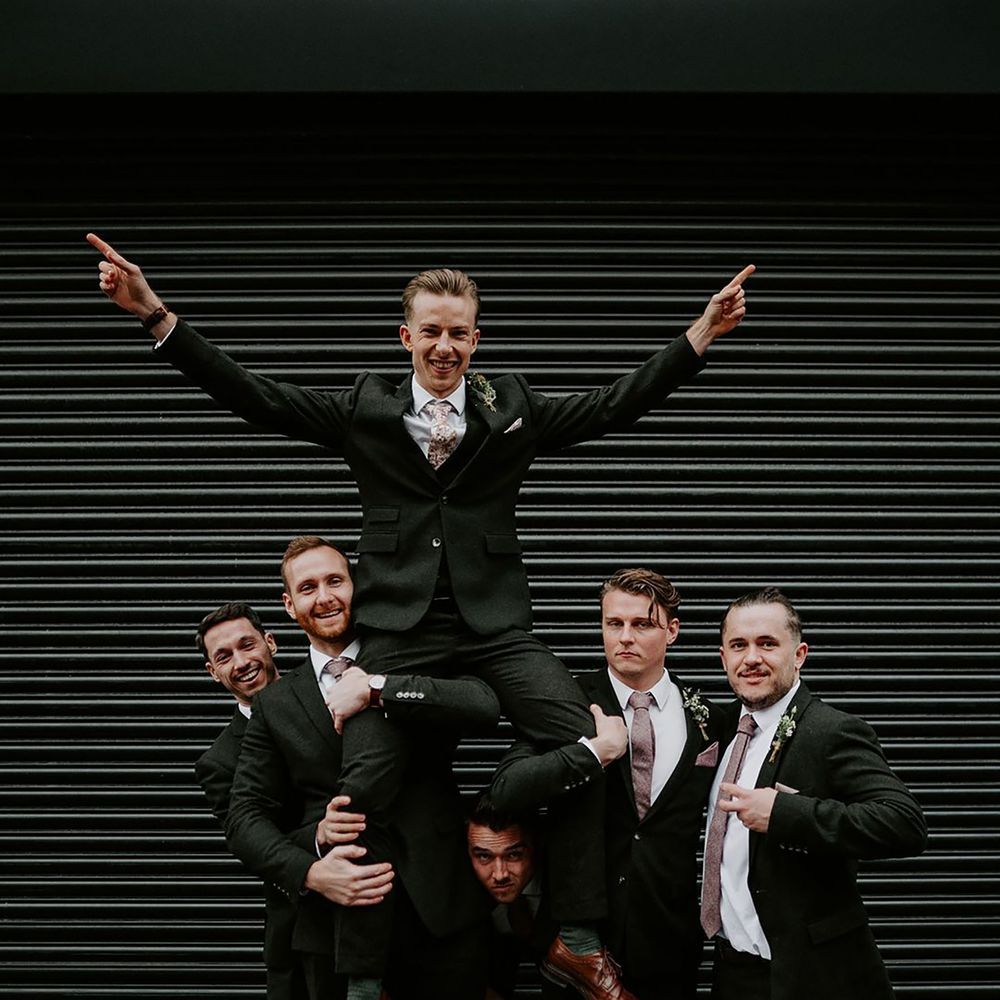 Groom is held up by his groomsmen on his wedding day