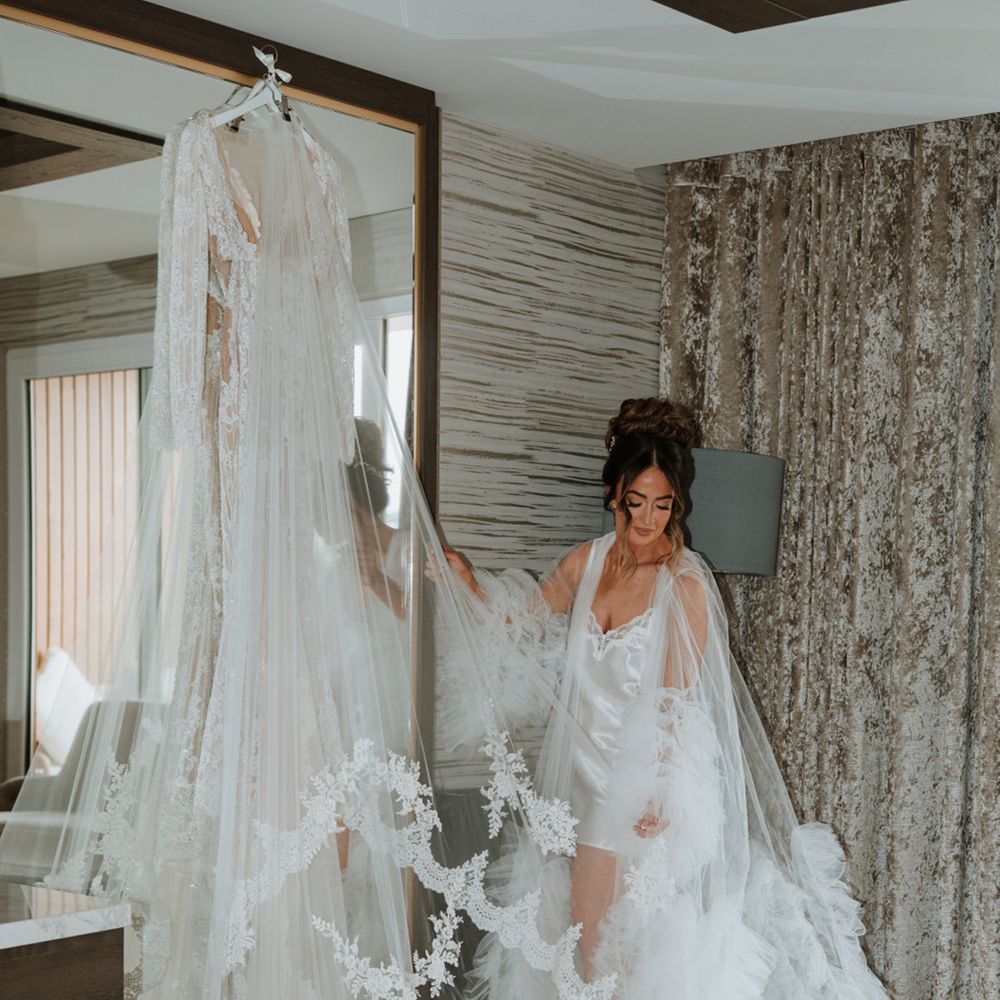 bride-in-ruffle-robe-looking-at-wedding-dress