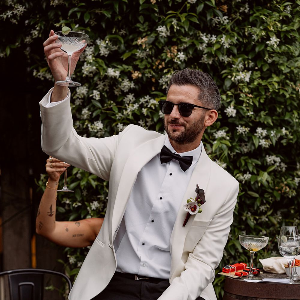 groom-in-white-tuxedo-raising-glass