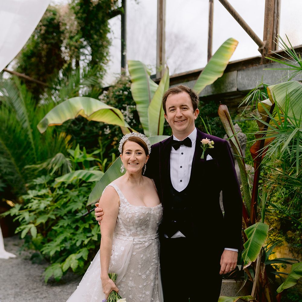 groom-in-purple-tux-poses-with-bride-in-sparkly-wedding-dress