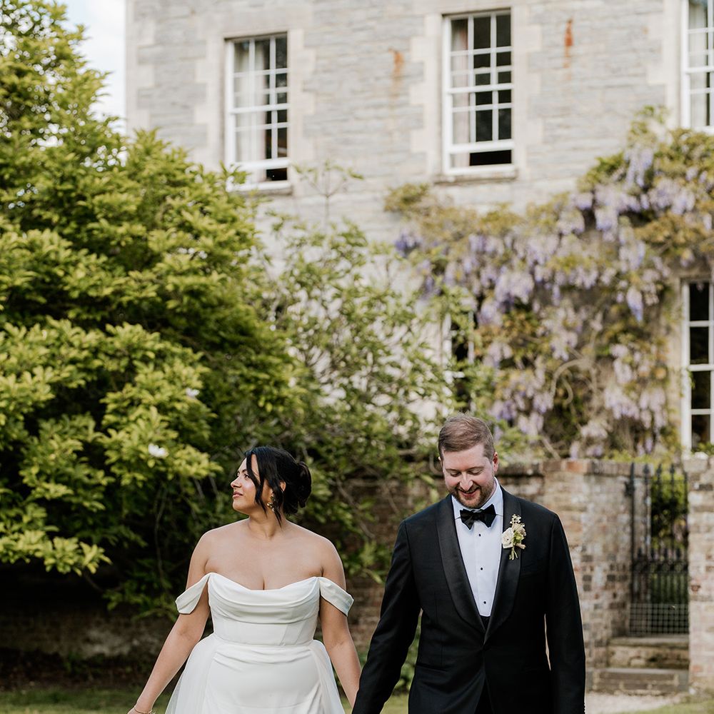 bride-in-off-the-shoulder-wedding-dress-walking-with-groom-in-black-tie