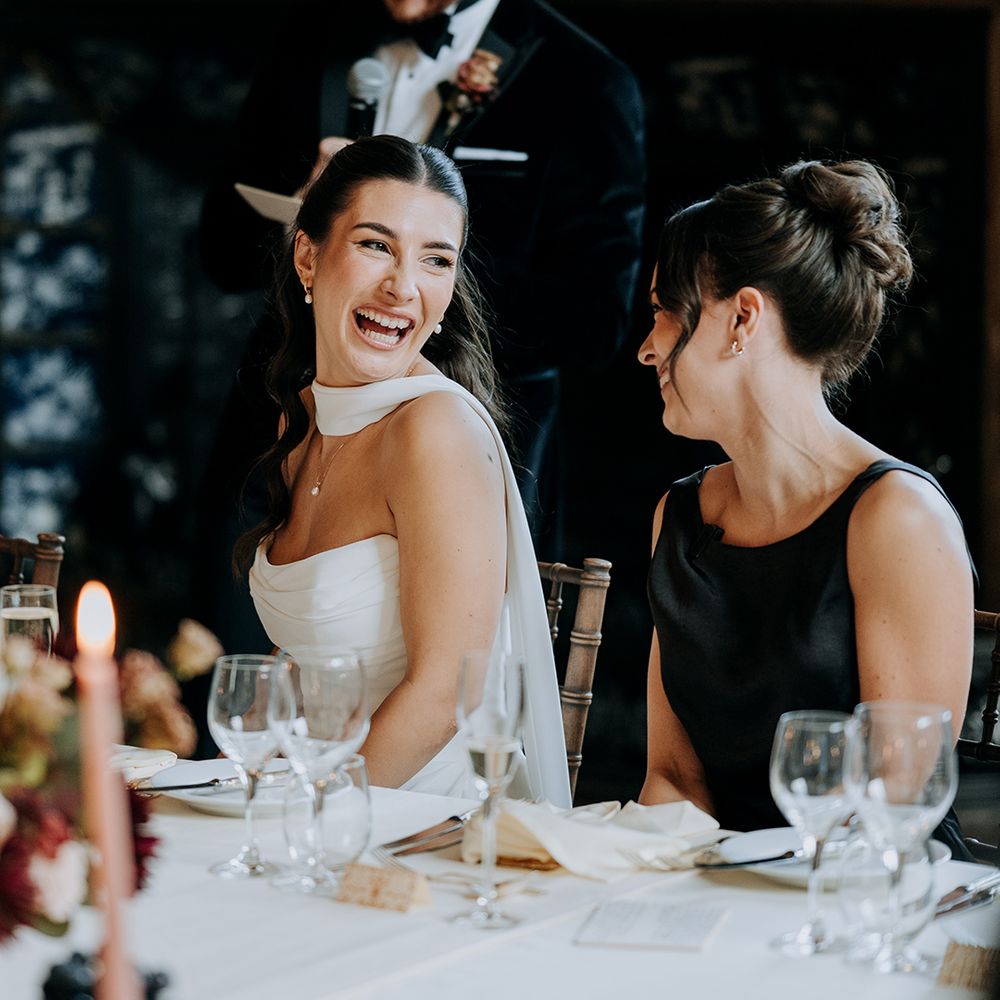 bride-laughs-with-bridesmaid-during-groom-speech